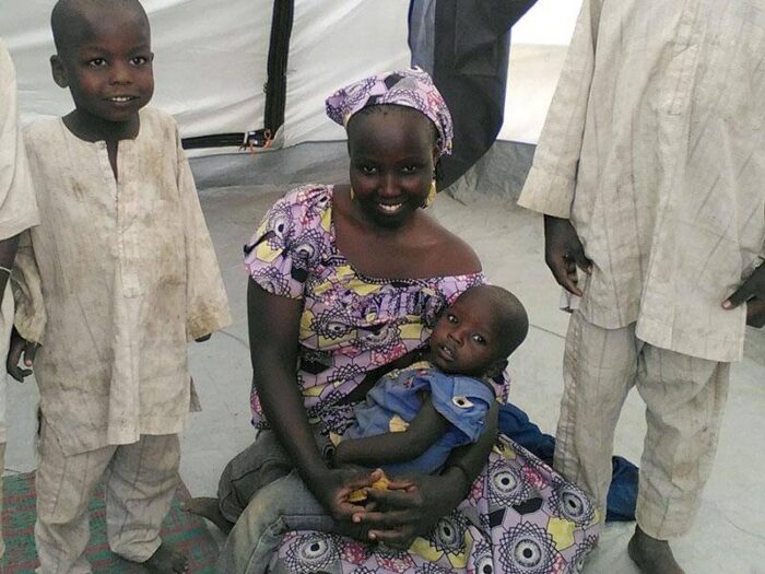 Eine Frau sitzt von Kindern umgeben in einem ShelterBox Zelt