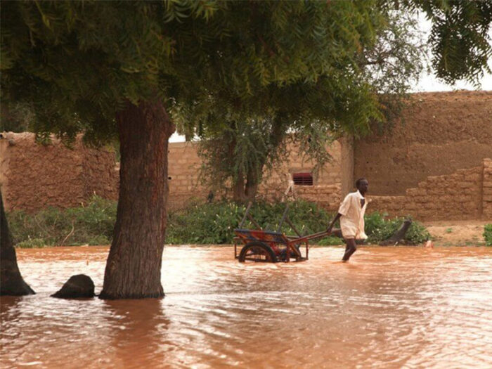 Junger Mann zieht einen Karren durch Hochwasser im Niger