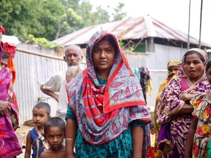 Eine Frau mit Kopftuch steht mit ihrer Community in Bangladesch