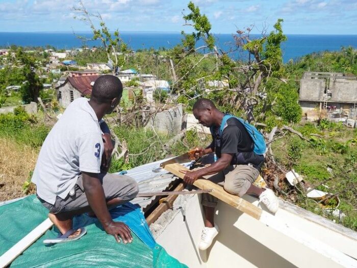 Zwei Männer reparieren ein Dach auf Dominica