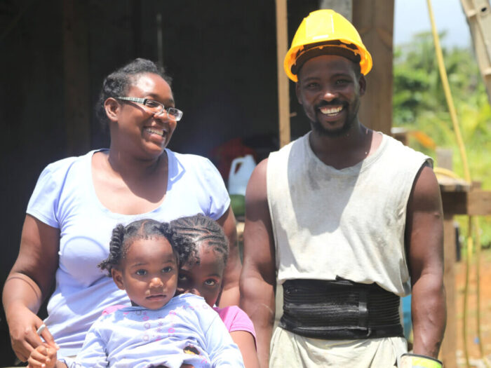 Eine lächelnde Familie hilft beim Wiederaufbau in Dominica