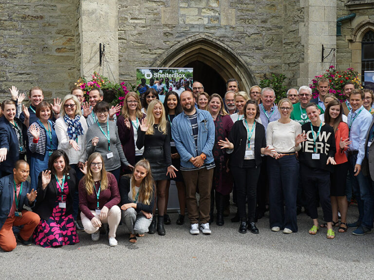 A large group of ShelterBox affiliates standing together posing for a photograph in front of an old building