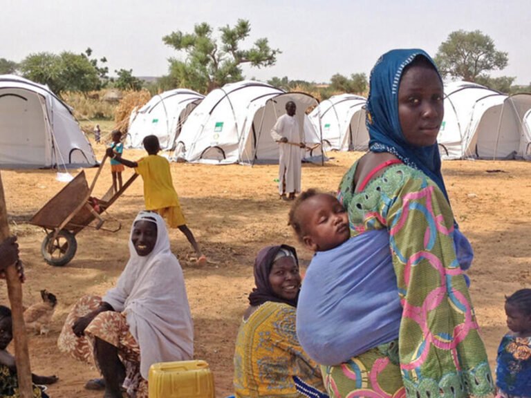 Frau mit einem Baby auf dem Rücken in einem Lager in Niger