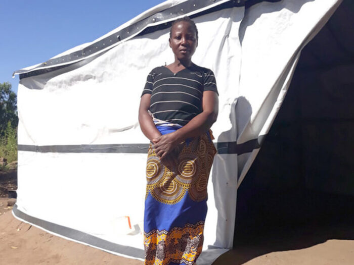 Eine Frau steht vor ihrer Notunterkunft in Malawi