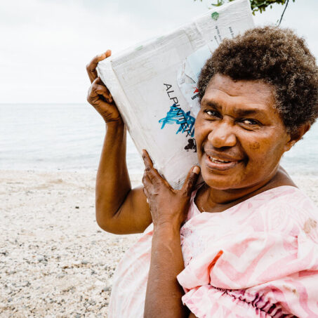 woman smiling and carrying a box on her right shoulder