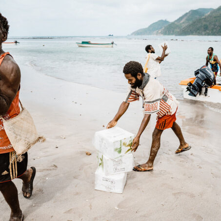 ShelterBox Hilfsgüter werden von einer Gruppe am Strand von Vanuatu transportiert