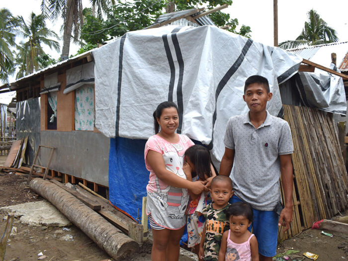 Eine fünfköpfige philippinische Familie posiert vor ihrem beschädigten Haus.