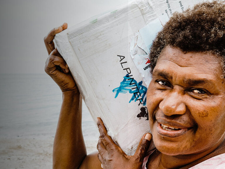 Eine lächelnde Frau, die eine Box auf ihrer rechten Schulter trägt