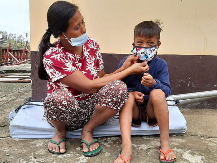 Mutter richtet die Gesichtsmaske ihres Sohnes auf den Philippinen