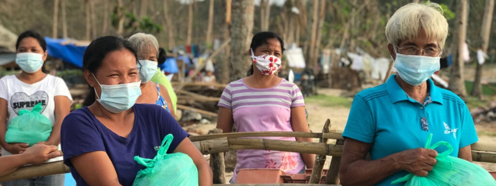 5 women wearing face masks and holding green bags