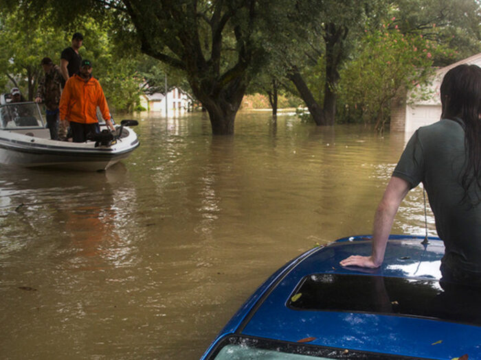 Man sat on a car to avoid the floodwater