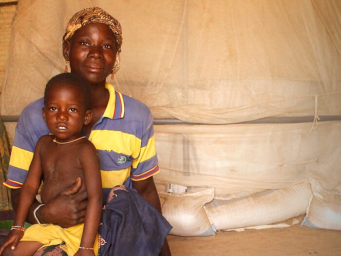 Eine Frau sitzt in einem Zelt und hält ihr Kind