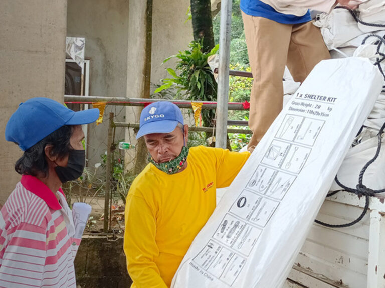 Menschen, die nach dem Taifun Rai auf den Philippinen Schutzausrüstung von einem Lastwagen entladen