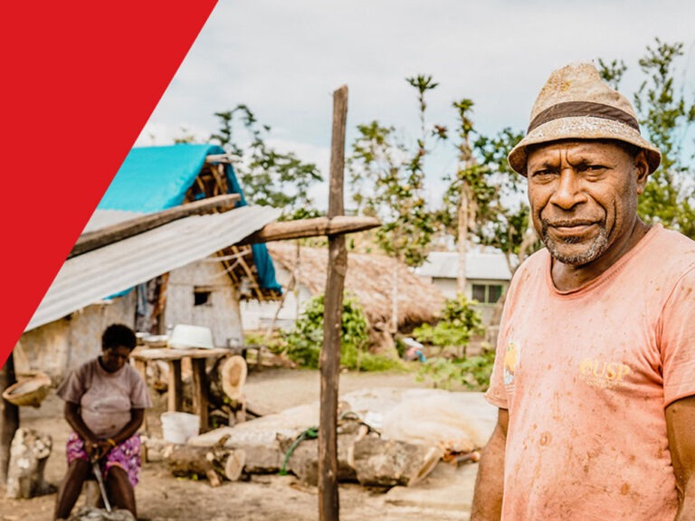Ein Mann steht vor einem reparierten Haus nach einem Sturm in Vanuatu