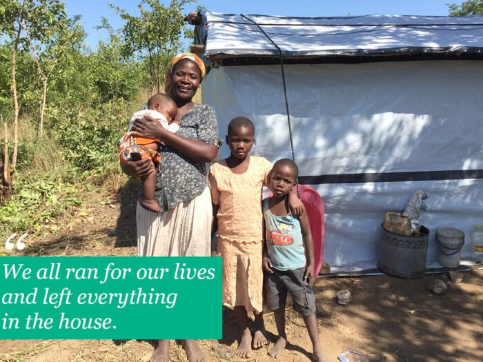Eine Frau steht mit Kindern vor einem Haus mit Planenwänden in Malawi