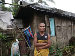 A man smiling outside his makeshift home