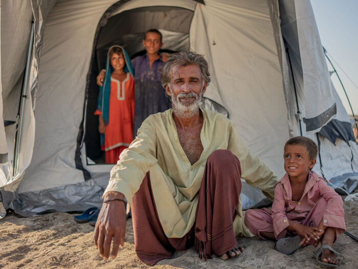 Familie lächelt vor ihrem Notfallzelt nach den Überschwemmungen in Pakistan