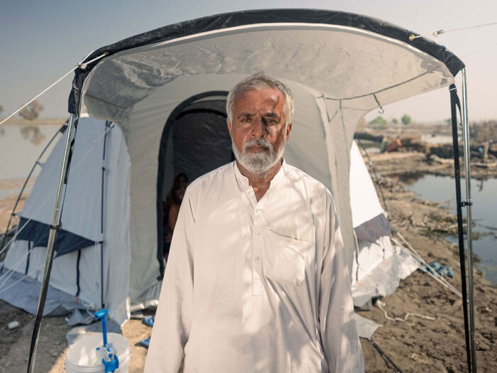 Mann steht nach Überschwemmungen in Pakistan ohne ein Lächeln vor einem Notfallzelt.