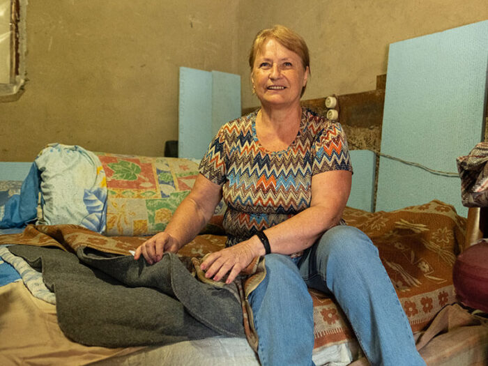 Smiling Ukrainian woman shows off thermal blankets in bedroom