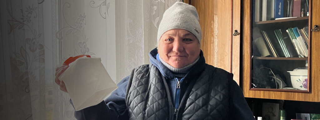Ukrainian woman in winter hat stands by window
