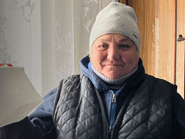 Ukrainian woman in winter hat stands by window