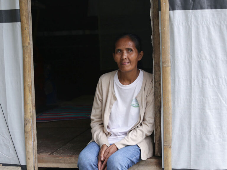 Eine philippinische Frau sitzt im Eingangsbereich ihrer Notunterkunft.