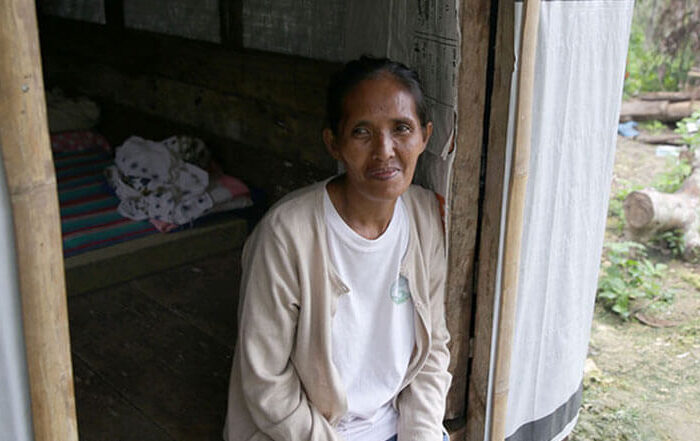 Filippino woman sits in entryway of her emergency shelter