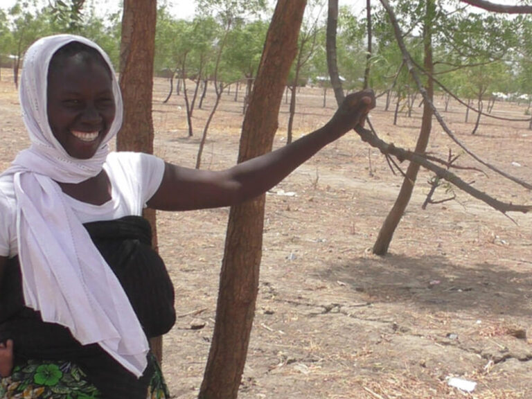 Woman wearing white head scarf next to a tree