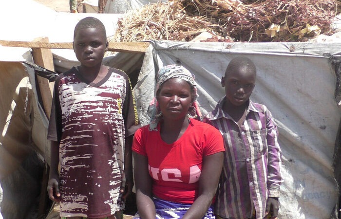 Eine Frau und zwei Kinder vor einer Unterkunft in Kamerun