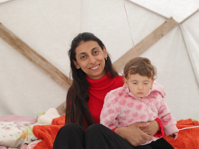 Eine Frau hält ein kleines Kind in einem Zelt in der Türkei