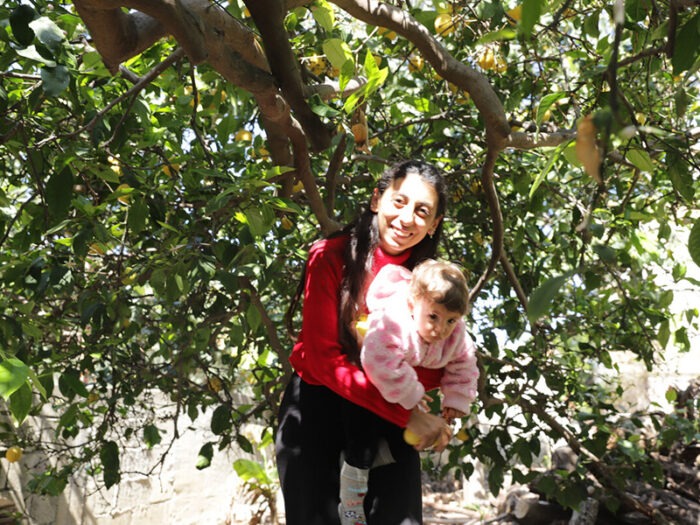 Eine Frau hält ein kleines Mädchen unter einem Zitronenbaum in der Türkei