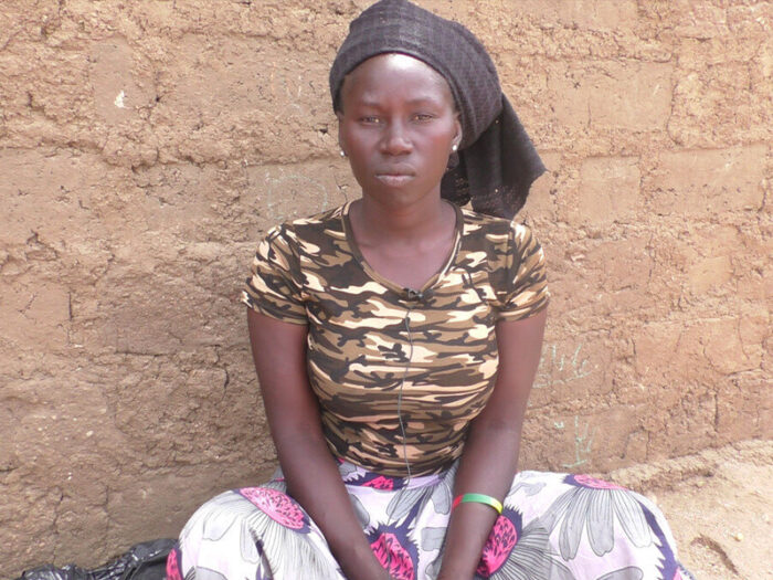 Eine sitzende Frau blickt in die Kamera