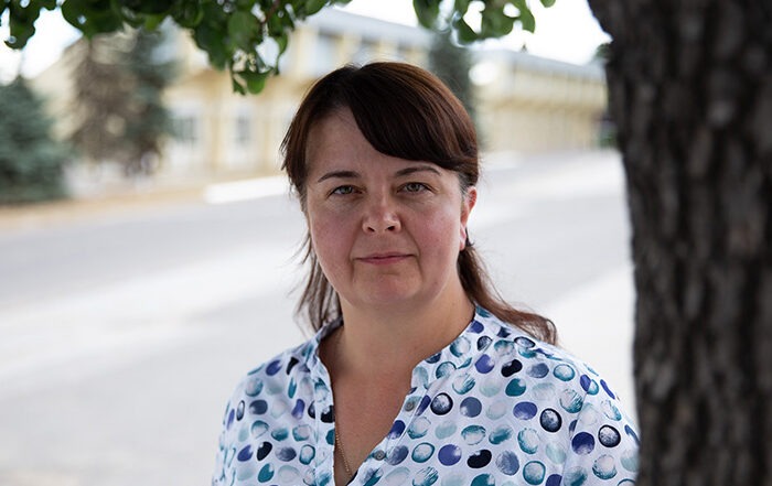 Head and shoulders of a lady facing the camera next to a tree