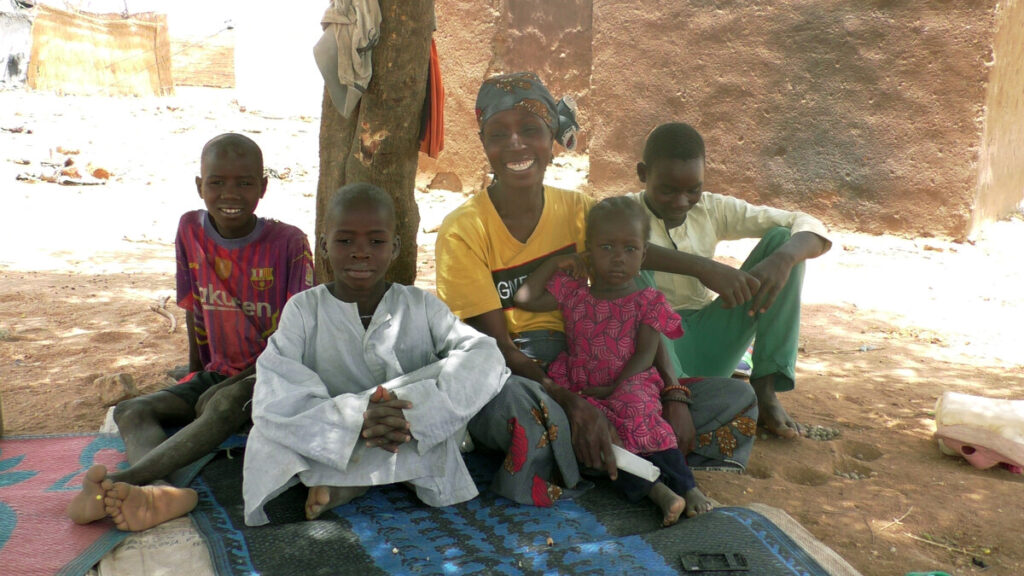 Eine Frau und Kinder sitzen unter einem Baum in Kamerun