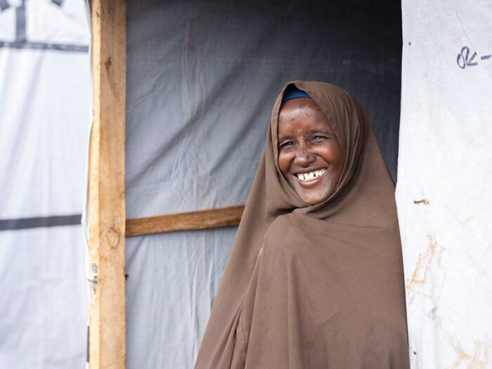Eine Frau mit brauner Kopfbedeckung lächelt im Eingang ihrer neuen Unterkunft in Somalia