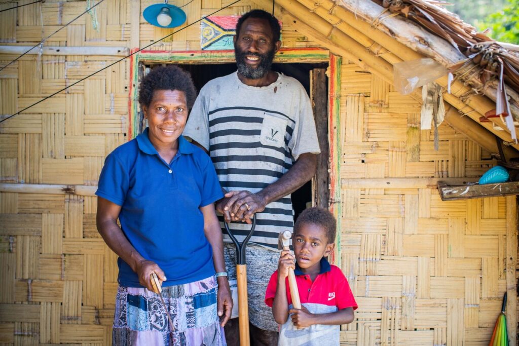 Eine Familie steht vor ihrem Zuhause in Vanuatu