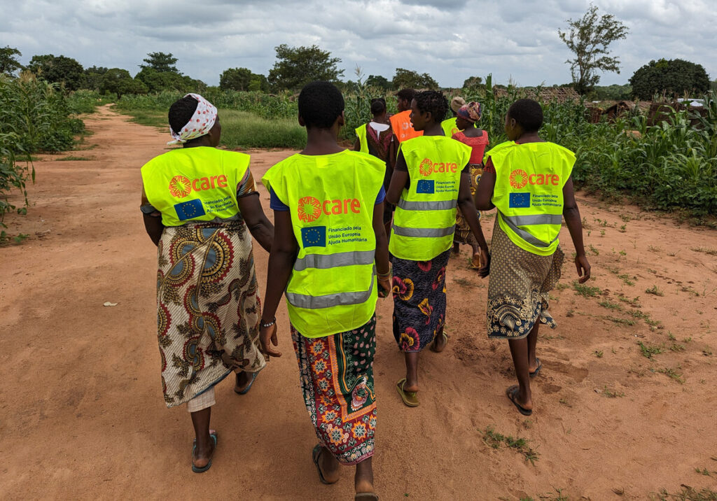 Four people walking away from the camera wearing his vis vests with CARE logo on it
