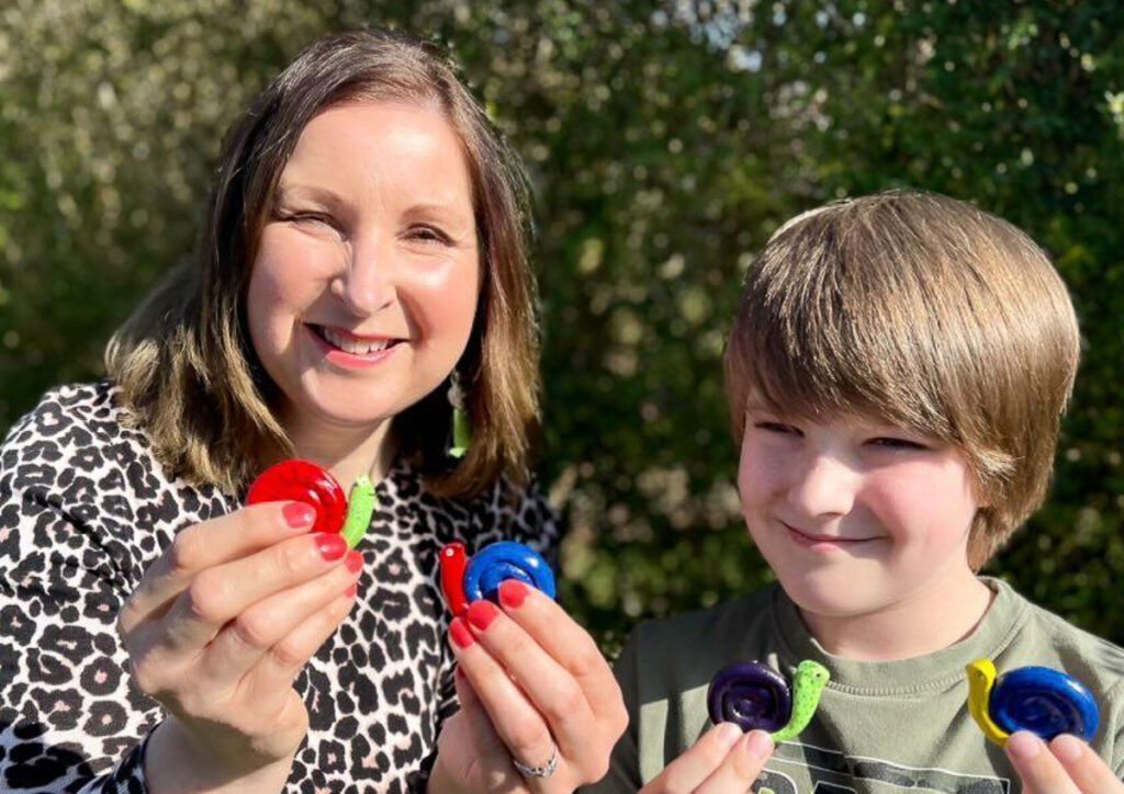 Woman and boy holding colourful hand made snails made of clay