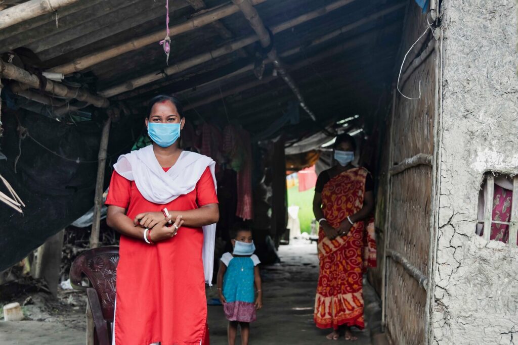 Eine Frau steht mit Familienmitgliedern in einem Haus in Indien, nachdem ihr vorheriges Zuhause durch den Zyklon Amphan zerstört wurde.