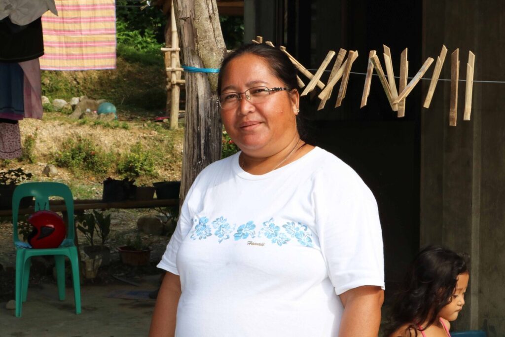 Frau in einem weißen T-Shirt vor ihrem Haus auf den Philippinen nach dem Taifun Goni