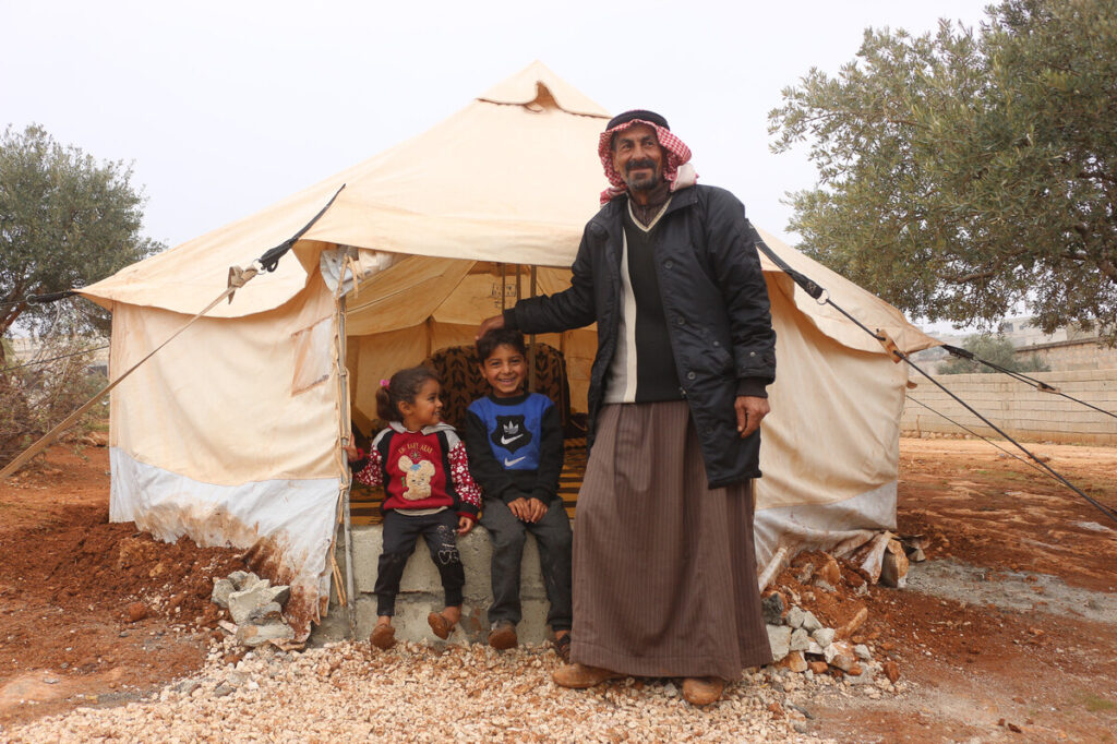 Mann und zwei Kinder stehen vor einem Zelt in Syrien