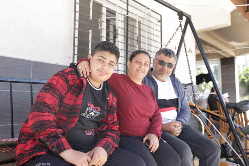 Mann, Frau und ihr Sohn sitzen in der Türkei vor ihrem Haus