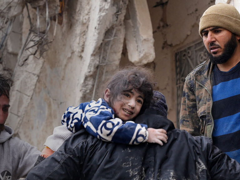 Anwohner retten ein Kleinkind aus den Trümmern eines zusammengestürzten Gebäudes in Syrien