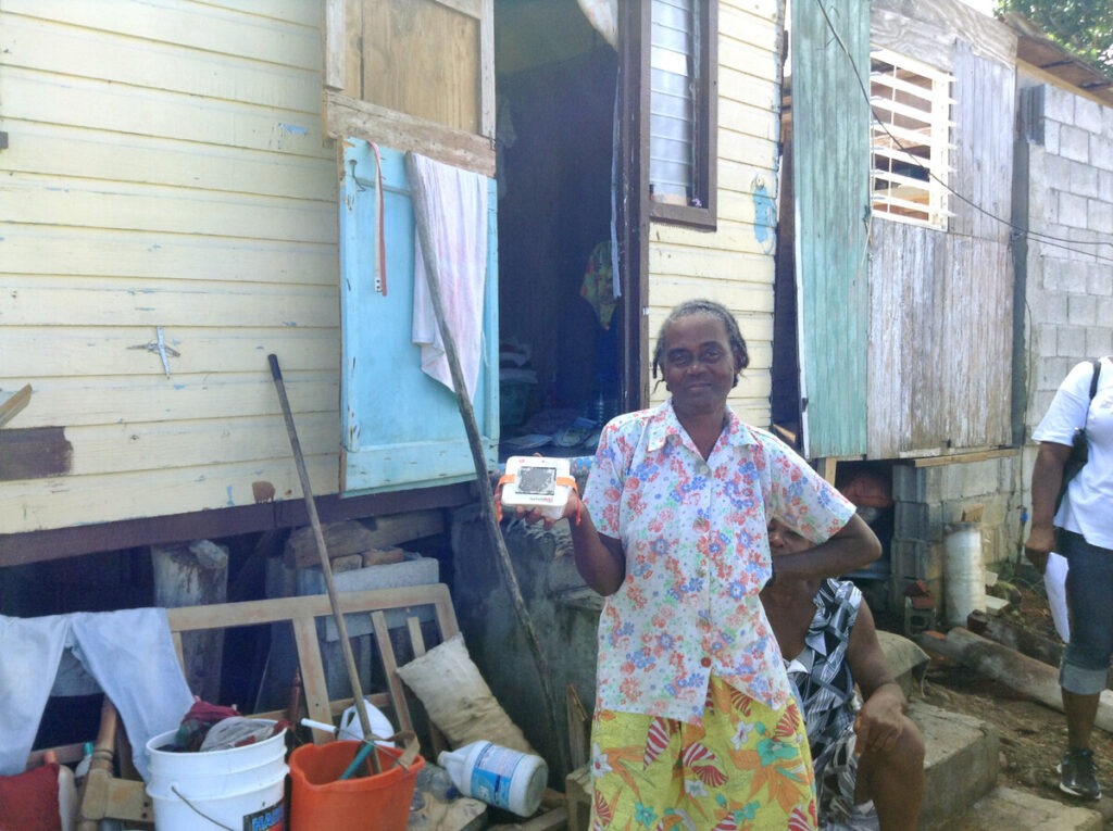 Eine Frau steht vor ihrem Haus und hält eine Solarlampe hoch