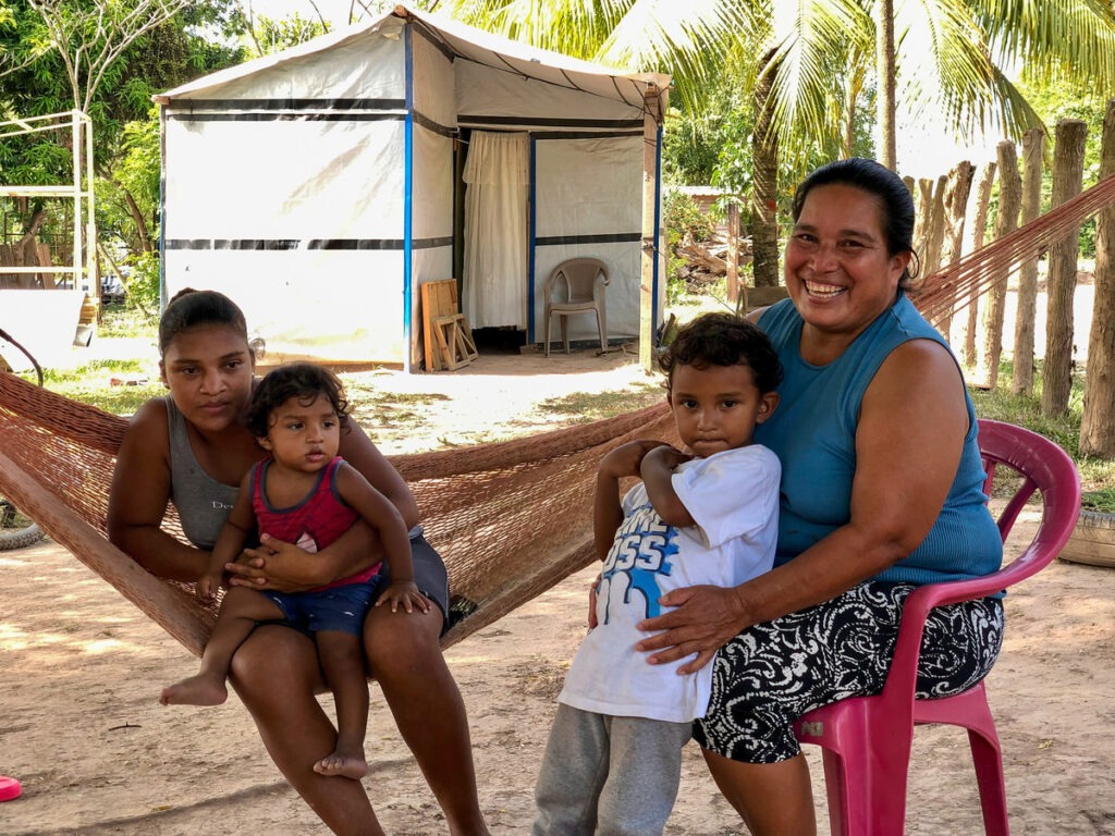 Eine Frau und drei Kinder saßen vor einer reparierten Unterkunft in Honduras nach den Hurrikanen Eta und Iota.