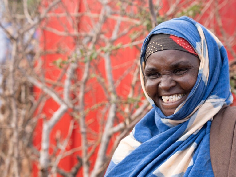 Frau lächelt vor rotem Hintergrund in Somalia