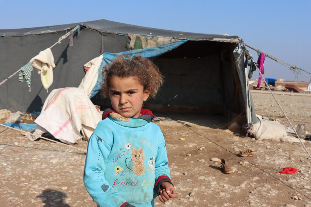 Ein Mädchen steht vor einem Zelt in Syrien