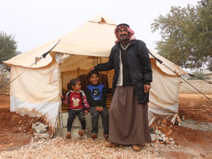 Ein Mann und zwei Kinder stehen vor einem Zelt in Syrien