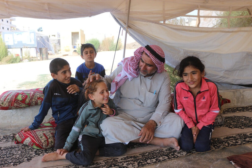 Ein Mann und drei Kinder sitzen in einem Zelt in Syrien