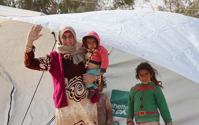Eine Frau und drei Kinder in warmer Kleidung vor einem Zelt in Syrien